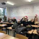 Dnia 06.12.2021 r. obchodziliśmy w szkole „Dzień Mikołaja”Na zdjęciu młodzież siedzącą w klasie w czapkach mikołajkowych