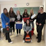 Uczennice prezentujące ciekawe zamienniki plecaka szkolnego: lodówka turystyczna,skrzynka na narzędzia samochodzik