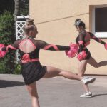 Dwie dziewczynki w strojach tanecznych czarno-różowych tańczy na boisku szkolnym