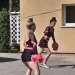 Dwie dziewczynki w strojach tanecznych czarno-różowych tańczy na boisku szkolnym
