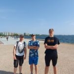 Trzech chłopców pozuje do zdjęcia na morskiej promenadzie z widokiem na Saloniki