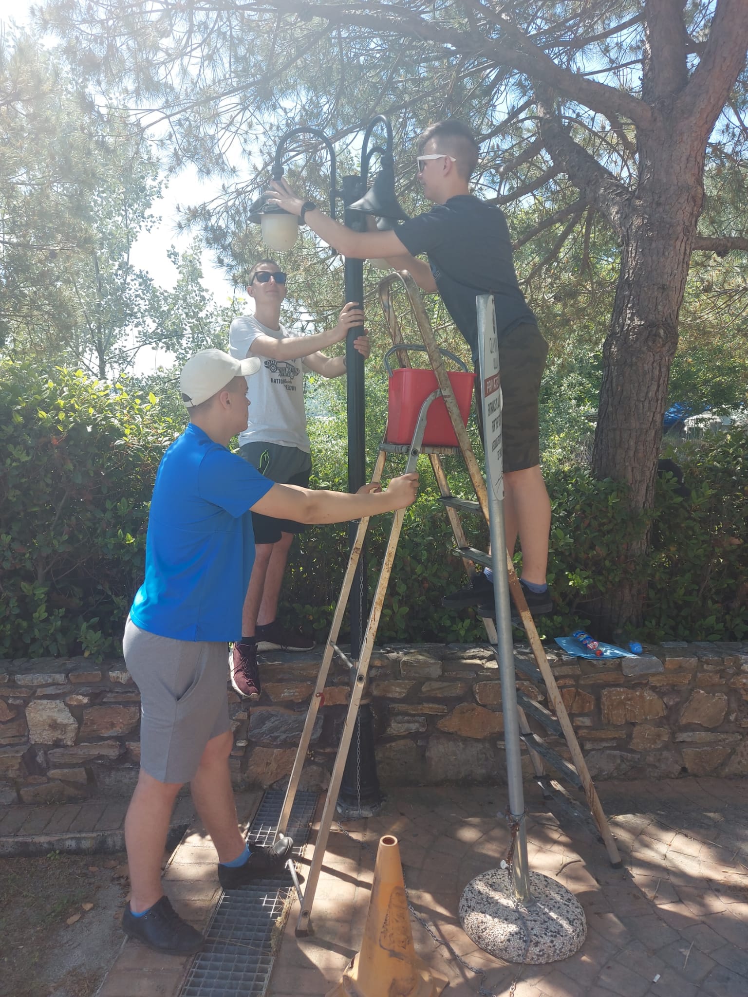 Uczniowie naprawiają lampę na terenie hotelu w Grecji