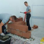 Dwóch uczniów buduje mur na olimpiadzie budowlanej