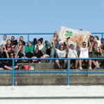 Na zdjęciu grupa uczniów kibicuje naszej drużynie z flaga z logo szkoły